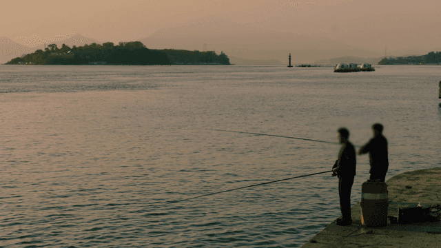 Two people fishing by the calm sea