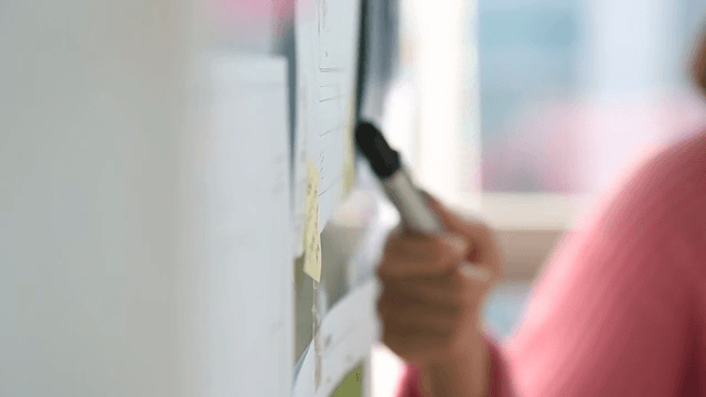 펜으로 보드를 가리키며 회의하는 손