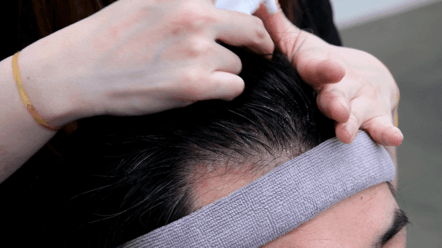 Hairdresser spraying treatment on scalp