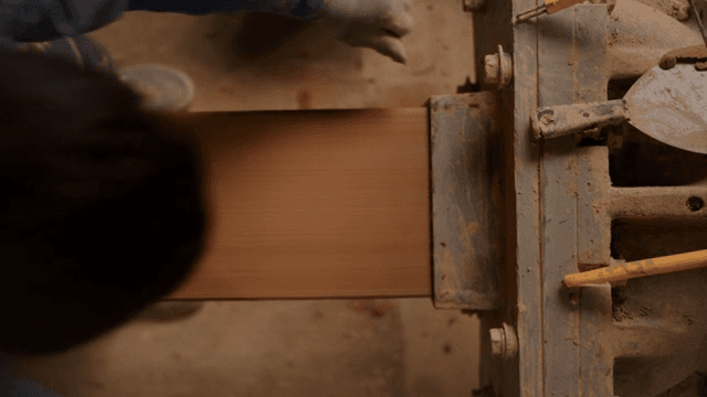 기계에서 점토를 다듬는 작업자