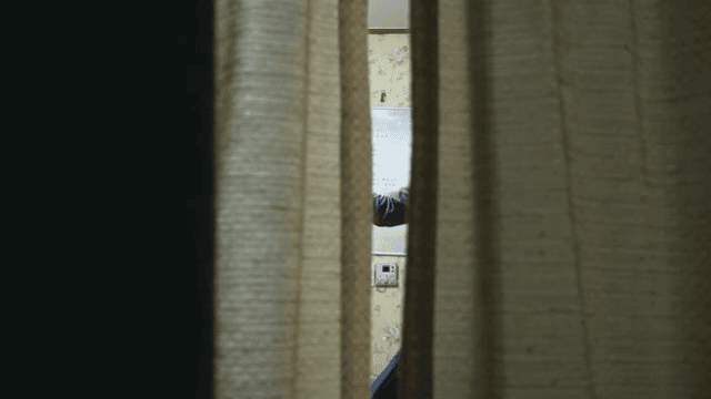 좁은 커튼 틈 사이로 보이는 춤 추는 남성