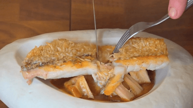 Fish being sliced on a white plate