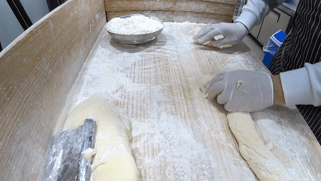 밀가루를 뿌린 표면에서 반죽을 하는 손