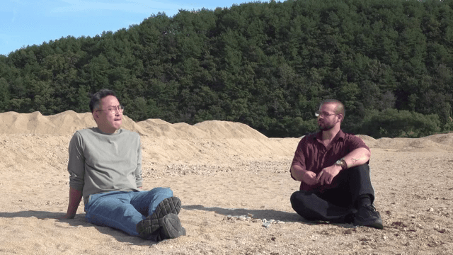 두 남자가 야외 모래밭에 앉아 있는 모습