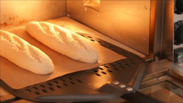 Scene of putting baguette dough into a heated oven