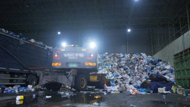 Garbage truck unloading waste in a recycling facility at night