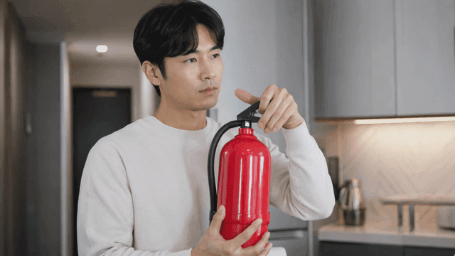 Man examining fire extinguisher at home