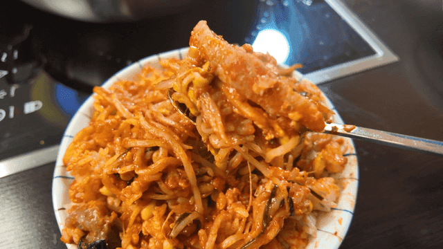 Spoon scooping up spicy braised anglerfish