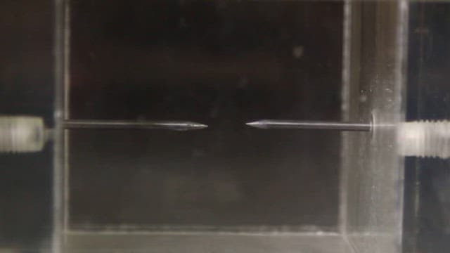 Two needles facing each other in a chamber