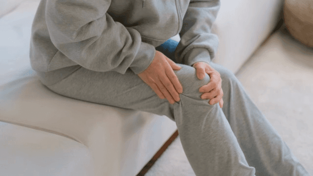 무릎이 아픈 회색 트레이닝복을 입은 사람