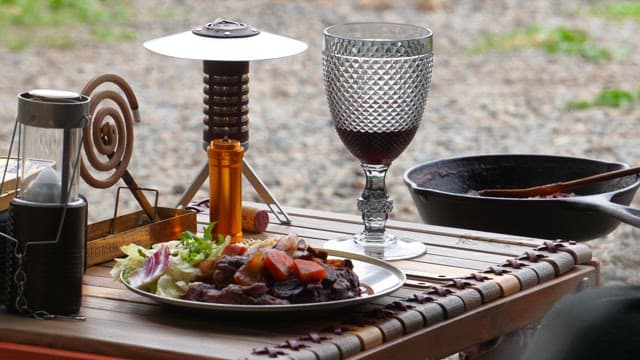 레드 와인과 캠핑 장비, 고기 요리가 있는 야외 식사 세팅