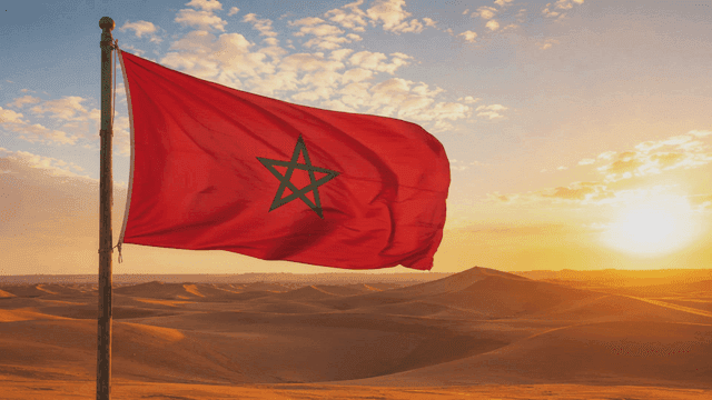 Moroccan flag fluttering in desert at sunset
