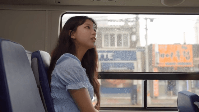 A woman gazing out a rainy bus window