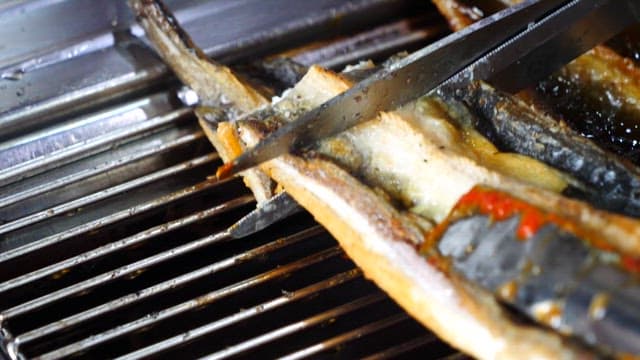 Person cutting various grilled eels with scissors