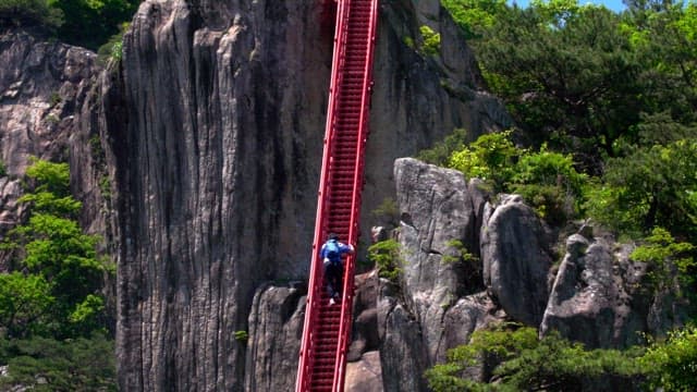 Hikers climbing the red, steep steps on a rocky mountain