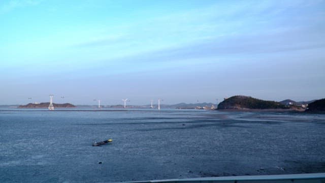 Vast sea with wind turbines and cable car lines against a peaceful sky during twilight