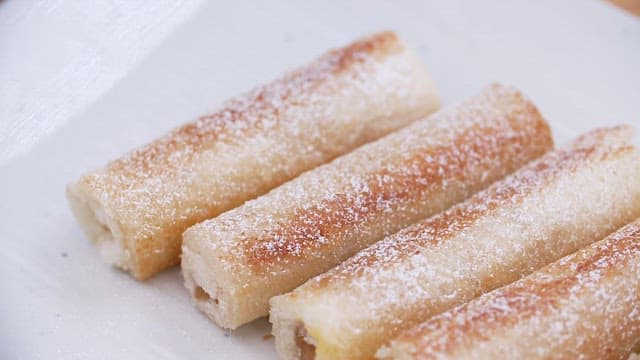 Close-up of sugar-dusted pastry rolls on a white plate