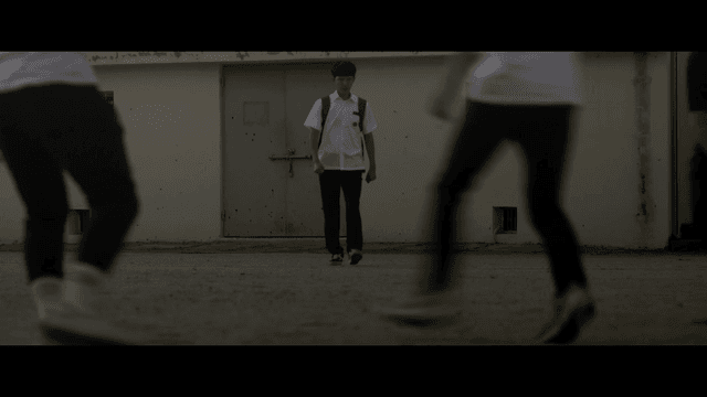 학교 운동장에서 축구 중인 학생들 사이로 걷는 학생