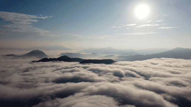 Mountains covered in clouds under the sun