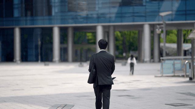Back view of a male office worker wearing a suit and going to work