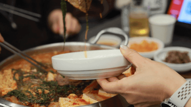 Hands plating spicy beef hot pot
