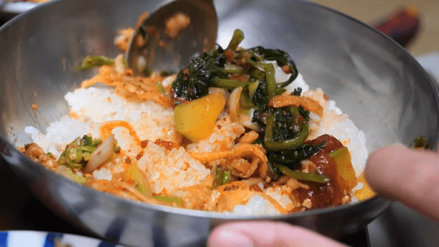 금속 그릇에서 비빔밥을 비비는 모습