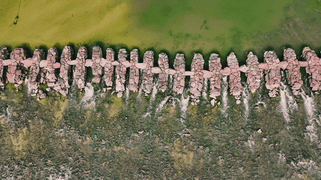 Aerial view of a stone bridge over a green river