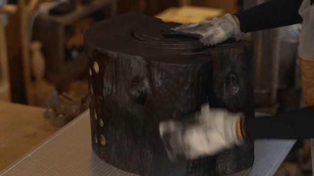 검은 나무 조각품을 수건으로 닦는 장인