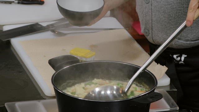 Transferring freshly cooked sujebi from the pot to a bowl