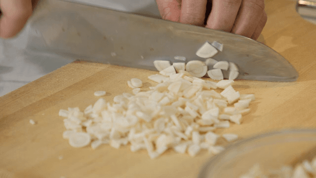 나무 도마 위에서 마늘을 써는 모습