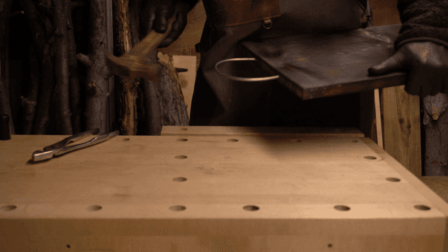 망치로 금속 와이어를 나무 판에 꽂는 장인