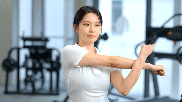 Woman stretching arms while facing forward at gym