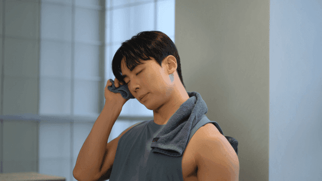 운동 중 수건으로 땀을 닦으며 휴식을 취하는 젊은 남성