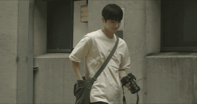 벽에 붙은 포스터를 보고 지나가는 카메라를 든 남성