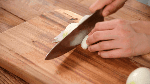Slicing an onion on a wooden cutting board