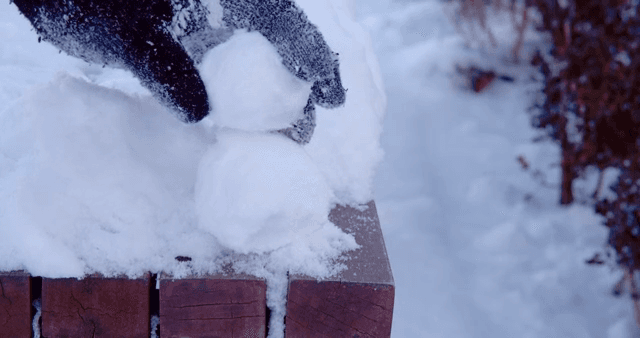 Making a snowman on a snow-covered bench