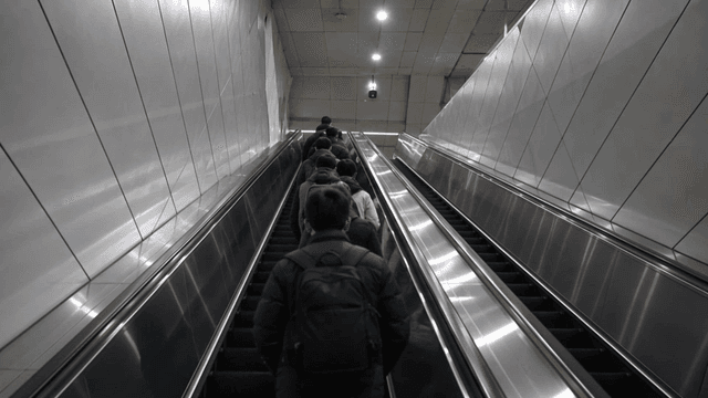 People ascending an escalator in a subway station