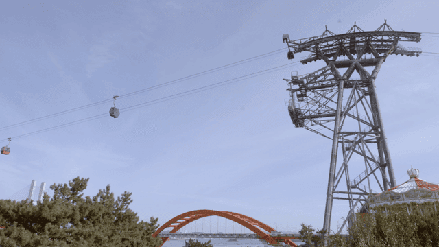 Sky with cable car passing over bridges and trees