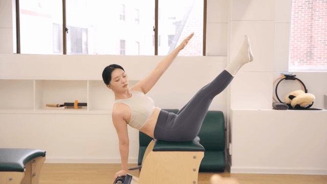 Woman practicing pilates using equipment indoors