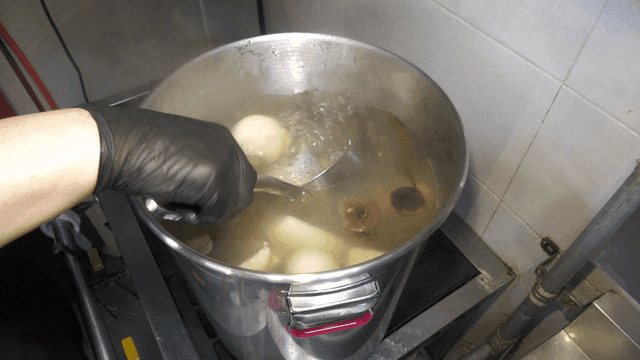 Ladle stirring broth with vegetables
