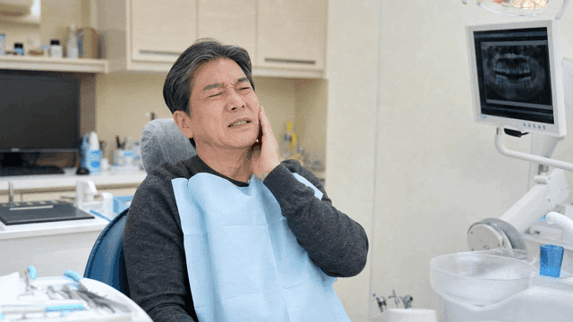 Elderly male patient suffering from toothache at dental clinic