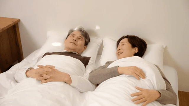 침대에 함께 누워 대화하는 노부부