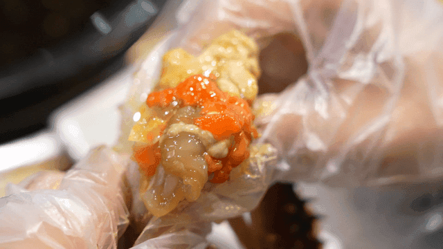 Hands squeezing out meat and intestines of soy sauce marinated crab