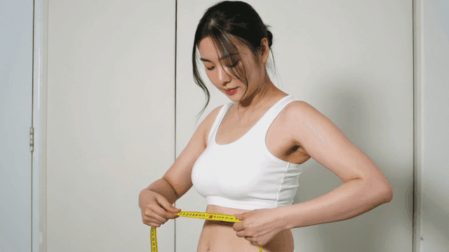 Woman measuring her waist with a tape