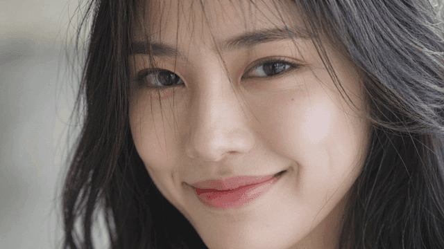 Young woman smiling naturally while looking straight ahead