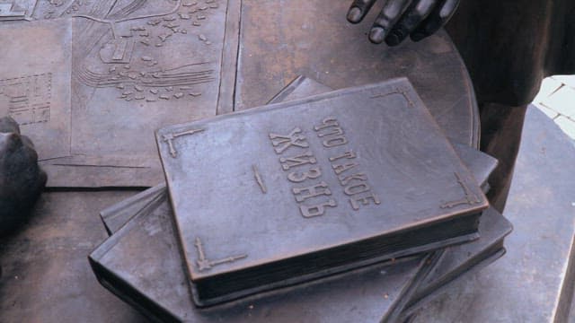 펜과 지도를 들고 있는 청동 조각상