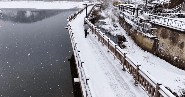 Man cleaning snow-covered riverside bridge