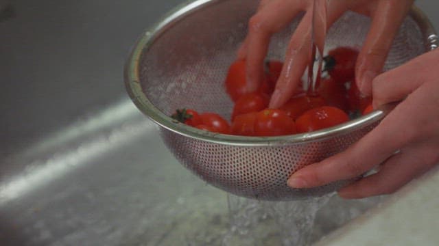 싱크대에서 신선한 토마토 씻기