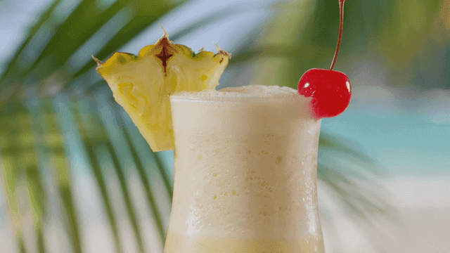 Tropical cocktail garnished with pineapple and cherries