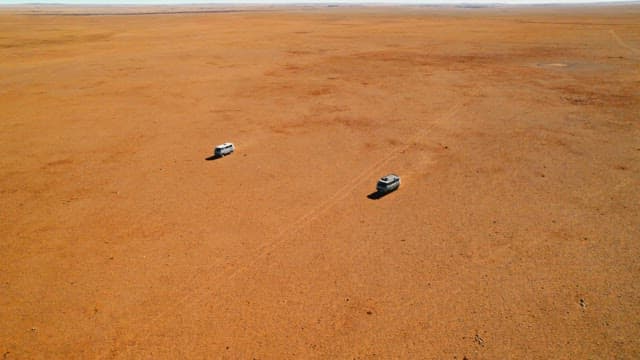 Two Vehicles Traveling Across Vast Desert